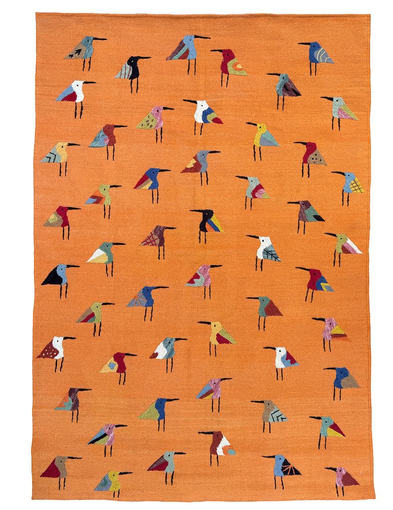 An orange woven SUZANI rug featuring a repeating pattern of stylised birds in various colours including blue, red, yellow, black, and white.