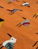 An orange woven SUZANI rug featuring a repeating pattern of stylised birds in various colours including blue, red, yellow, black, and white.